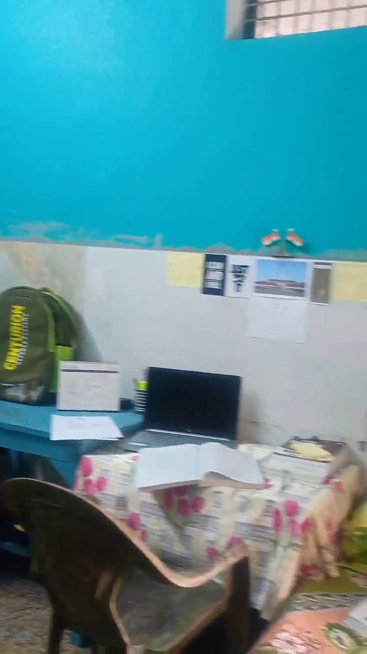 A study desk with a laptop and notes on the wall