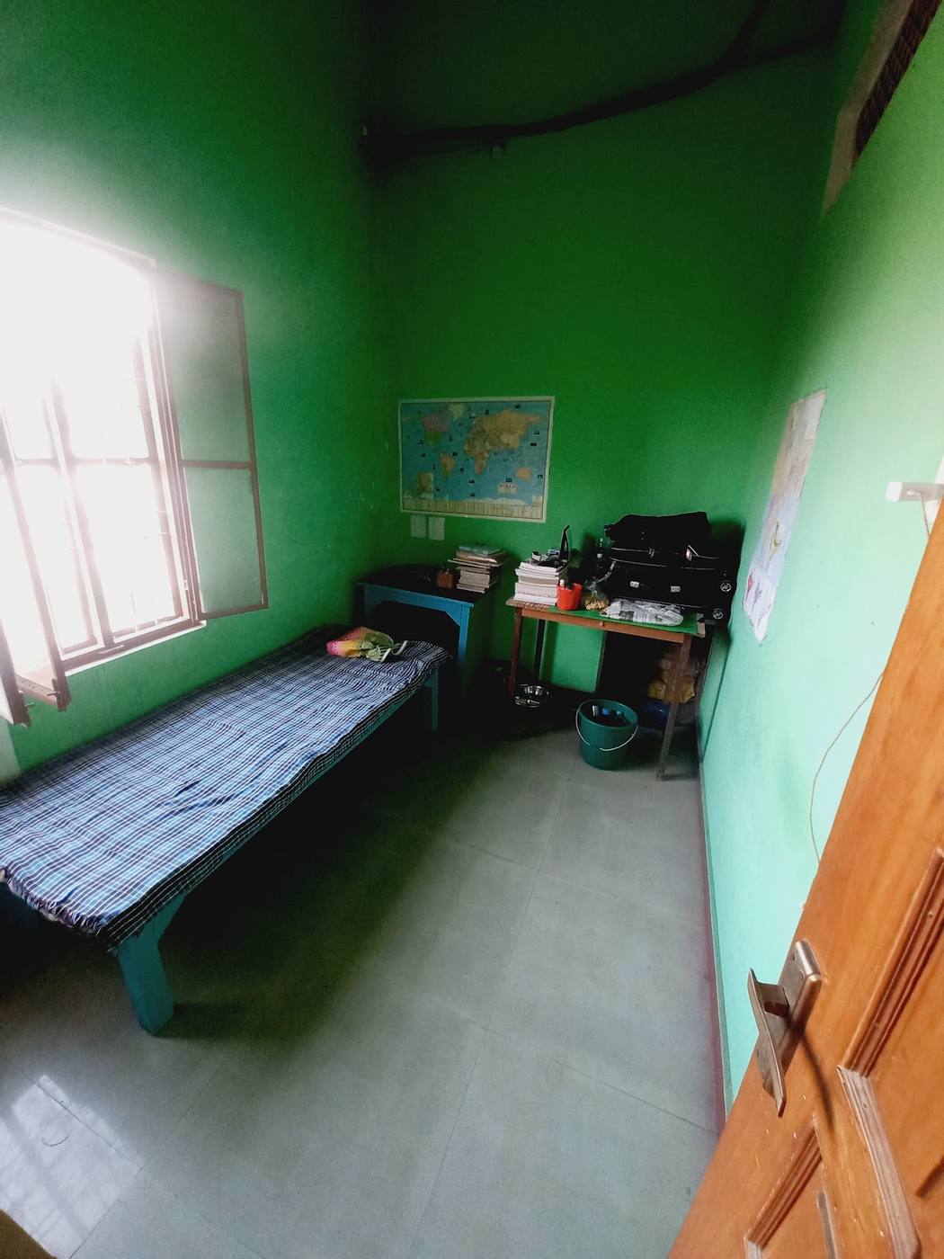 A room with a bed, study tables and a world map