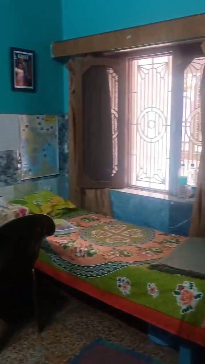A bed beside a grilled window, in a turquoise room